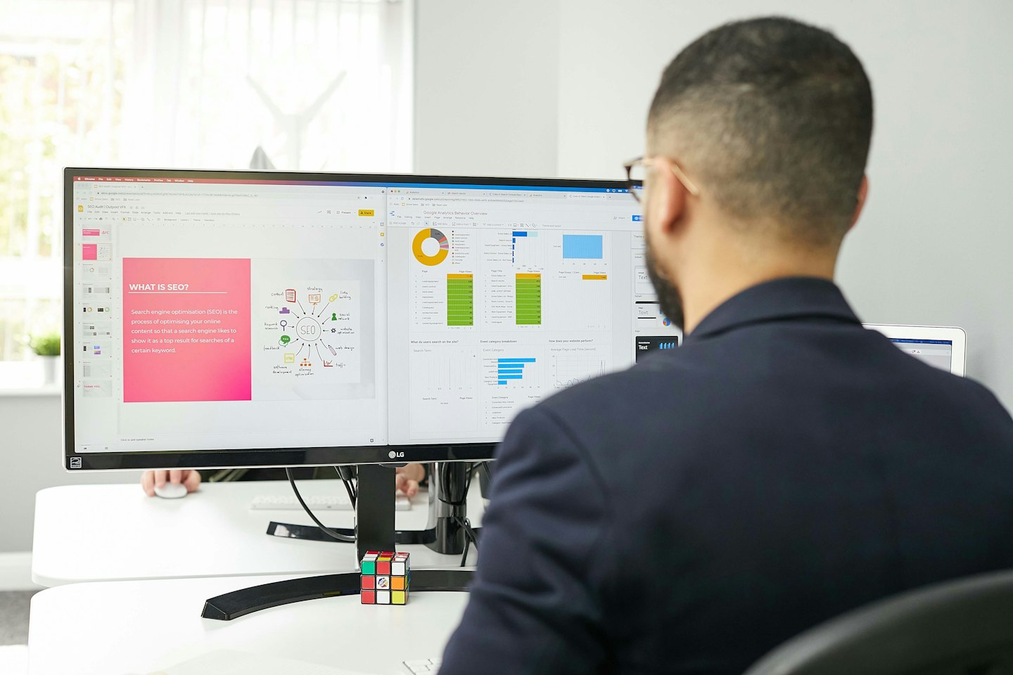 Mann arbeitet an zwei Computermonitoren mit SEO- und Analyse-Daten.
